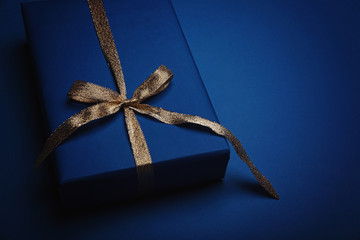 Gift box wrapped in classic blue paper with a gold ribbon. Color of the year 2020, Classic Blue. Copy space.