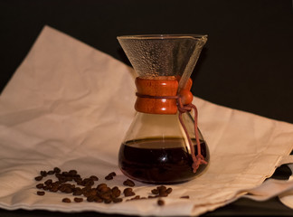 On black background and dense coarse cloth stands glass vessel for brewing strong and invigorating...