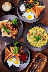 Traditional breakfast with fried eggs, sausages, beans, mushrooms, grilled tomatoes and bacon on wooden background. Top view