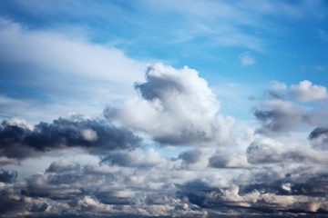 Cumulus white and gray clouds on a blue sky. Beautiful dreamy scene of air clouds on blue sky background.