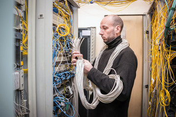 A surprised, bewildered and confused technician looks at a multitude of tangled wires. A specialist...