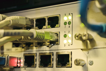 Front panel of an old internet switch. Network interfaces and cables are interconnected. Communication wires connect to equipment ports in the server room of the data center.