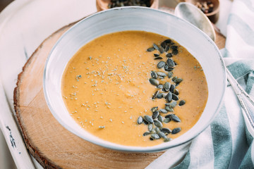 A bowl with pumkin soup decorated with pumkin seeds