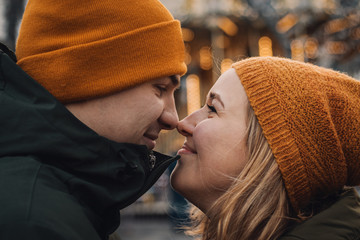 Young romantic couple is having fun outdoors in winter before Christmas. Enjoying spending time together in New Year Eve. Two lovers are hugging and kissing in Saint Valentine's Day.