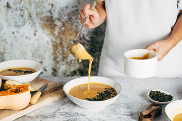 A woman serving pumpkin soup at lunch time