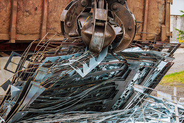 A grapple truck loads scrap industrial metal for recycling.