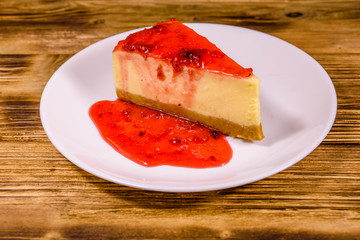 White plate with cheesecake New York and raspberry jam on wooden table