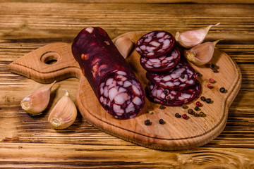 Cutting board with sliced salami sausage and garlic on a wooden table