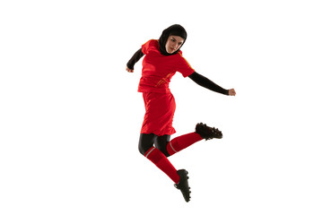 Fototapeta na wymiar Arabian female soccer or football player isolated on white studio background. Young woman kicking the ball back, training, practicing in motion and action. Concept of sport, hobby, healthy lifestyle.