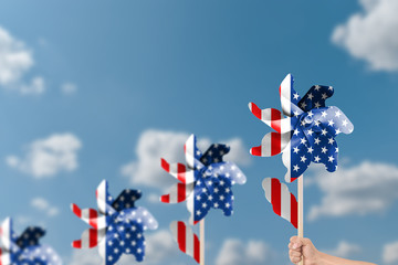 Hand holding wind turbine patriotic of USA over blue sky background.