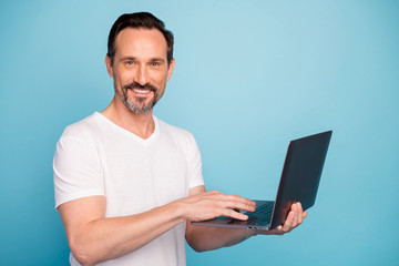 Close-up portrait of nice attractive cheerful cheery successful guy tech support geek using laptop developing career isolated on bright vivid shine vibrant teal green blue turquoise color background