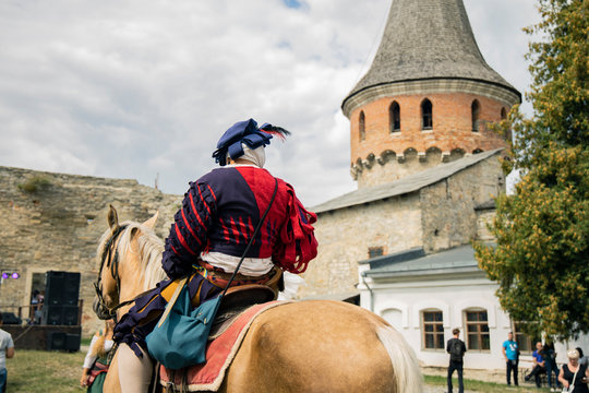 historical reconstruction hobby passion picture of medieval male rider on horse back to camera in castle yard space with fortress tower background landmark view
