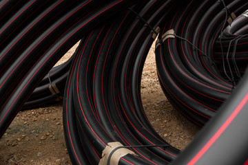 Black rubber or plastic pipes with a red lines as a construction material and equipment at building...