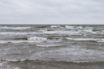 Seaside view of Baltic sea waves on a cloudy and stormy winter day near beach.