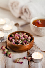 Concept of spa treatment with roses. Dry flowers in a bowl, herbal tea, towel, candles as decor. Atmosphere of relax and pleasure, comfort, anti-stress and detox procedure. Luxury lifestyle. 