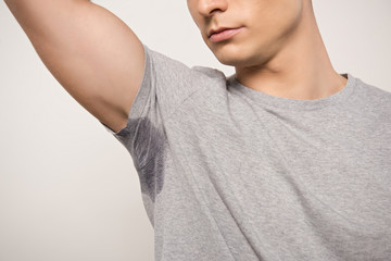 cropped view of young man in grey t-shirt with sweaty underarm isolated on grey