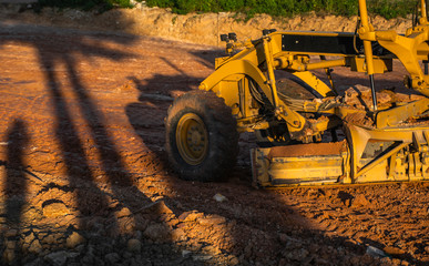 Grader is working on road construction. Grader industrial machine on construction of new roads. Heavy duty machinery working on highway. Construction equipment. Compaction of the road.