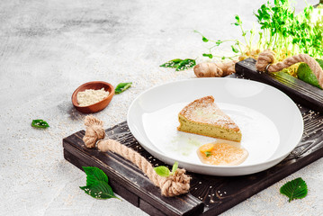Sugar-free and gluten-free casserole with agave syrup on beautiful white plate on dark rustic tray on light concrete background in beautiful composition. Close-up. Space