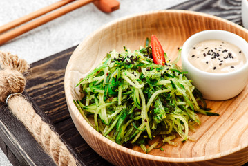 Pan-Asian food. Vegetable salad with chuka, cucumber and sesame seeds on round wooden plate