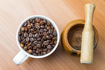 Obraz premium coffee mug filled with coffee beans and vintage rustic wooden coffee crusher against wooden background