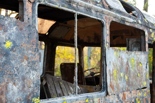 An old rusty bus with broken windows and with traces of paint stands in a forest. Bunker at the tactical paintball playground. Closeup view