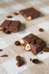 pieces of chocolate with hazelnuts and coffee beans on a brown tablecloth