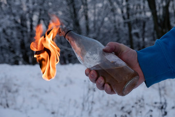 Molotov cocktail in a male hand in front of a prosk