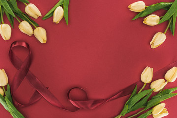 top view of tulips with silk ribbon isolated on red with copy space