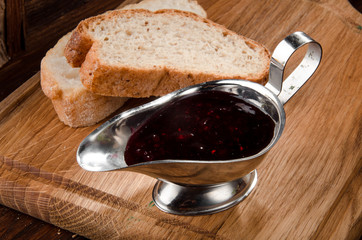 burgundy berry sauce in an aluminum sauce-pan on a wooden background with bread