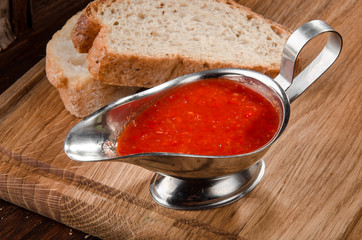 red sauce in an aluminum sauce-pan on a wooden background with bread