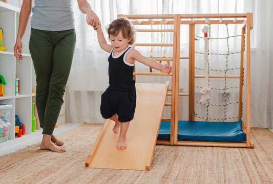 Child At An Early Age Of 1.5 Years Is Engaged In The Home Children's Wooden Sports Complex.