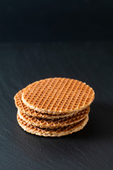 Food Concept Stroopwafel, crispy caramel syrup Dutch waffles  on black slate stone background