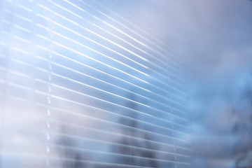 Abstract horizontal jalousie lines, blue sky and trees reflection on window's glass. Perfect background for your text. Copy space.