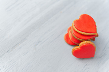 cookies in the shape of hearts piled in a stack on a light wooden table