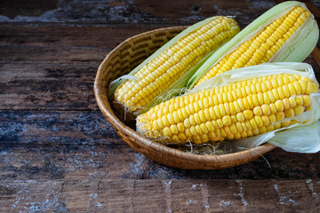 Fresh corn in basket on  on wooden table