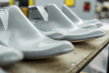 Plastic lasts used in the manufacture of shoes. Row of plastic shoe lasts used to manufacture modern day shoes. A lot of plastic last shoe on a wooden shelf. The equipment used for shoe design.