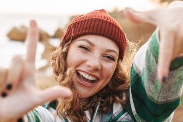 Image of joyful young woman showing photo frame while walking outdoors