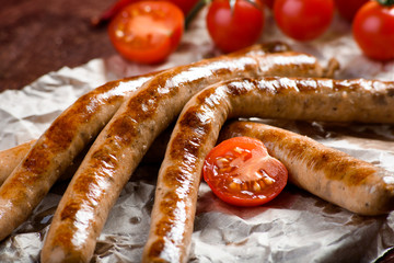 Fried sausages with sauces and herbs on a wooden serving Board. Great beer snack on a dark background. Top view with copy space
