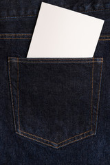 Blank white card in the back pocket of dark blue jeans. Copy space