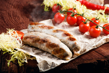 Fried sausages with sauces and herbs on a wooden serving Board. Great beer snack on a dark background. Top view with copy space