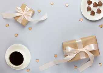 Banner of Valentine's Day. A Cup of coffee, a gift boxes and a heart-shaped chocolate on a neutral grey background.