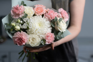 Close-up flowers in hand. Florist workplace. Woman arranging a bouquet with roses, chrysanthemum, carnation and other flowers. A teacher of floristry in master classes or courses
