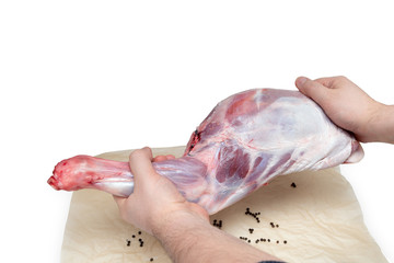 Raw lamb leg in male hands isolated on white background.