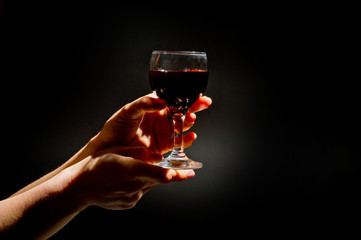 Naklejka na ściany i meble .female hand with a glass of wine on a dark background