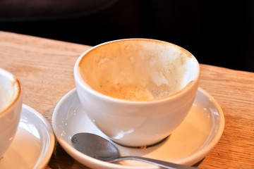 empty and dirty cups of coffee after breakfast. Dirty coffee cups with milk foam. Mess on the table after breakfast with dirty mug. Afterparty. White porcelain cup with leftover cappuccino. 