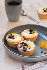 homemade shortbread tartlets or cupcakes with delicate cream and orange jam, decorated with chocolate chips. natural sweets concept. cozy tea party