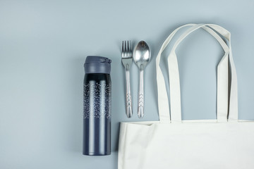 Eco Shopping bag, Stainless Steel spoon and fork, water bottle on gray background. Environmental...