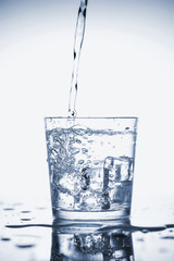 Clear mineral water is poured into a glass with ice.
