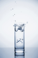 Clear mineral water splashes in a glass with ice.