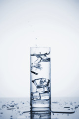 Clear mineral water splashes in a glass with ice.